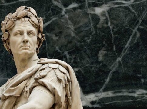 Marble statue of Julius Caesar with a serious expression against a dark background