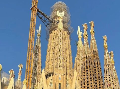 Construction view of the Sagrada Familia with cranes and intricate towers against a blue sky
