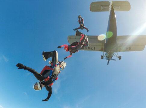 Skydivers freefalling below a small aircraft blue sky