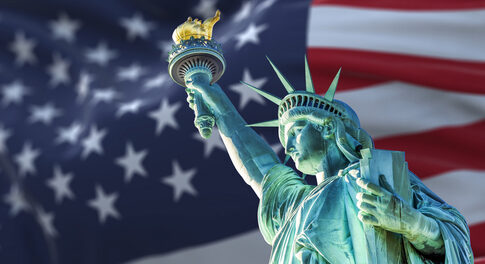 Statue of Liberty holding a torch with an American flag background