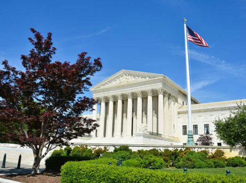 Supreme Court building with American flag and trees.