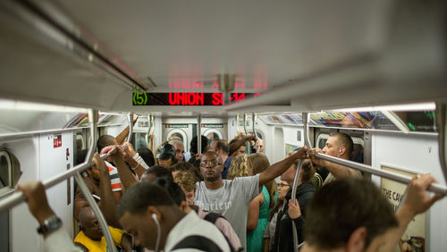 Crowded subway train with standing passengers sign reads Union St