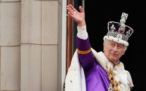 King Charles III in coronation attire waving.