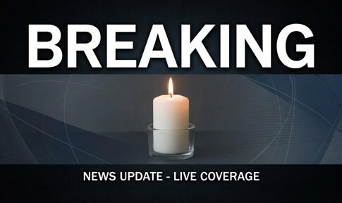 A lit candle with a breaking news banner above it