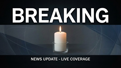 A lit candle with a breaking news banner above it