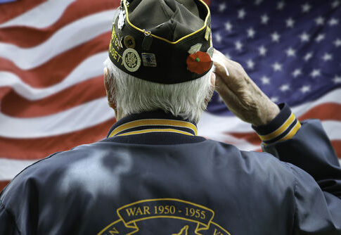 Veteran saluting in front of American flag.