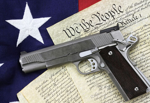 Handgun resting on historical document with American flag backdrop