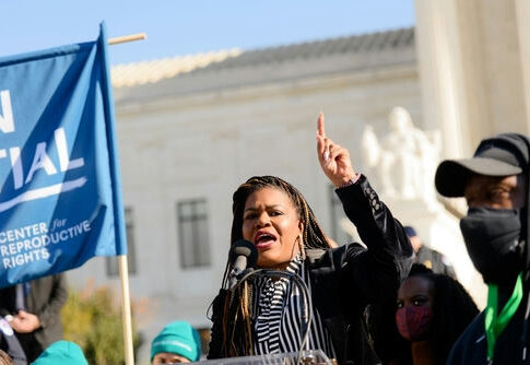 Speaker raises hand while addressing crowd at outdoor rally