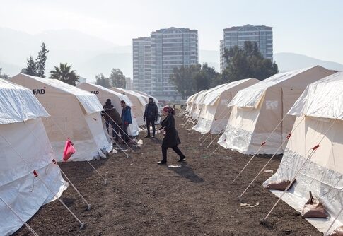 A temporary shelter area with tents and people walking around