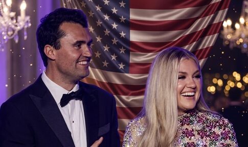 A smiling couple in formal attire standing in front of an American flag backdrop