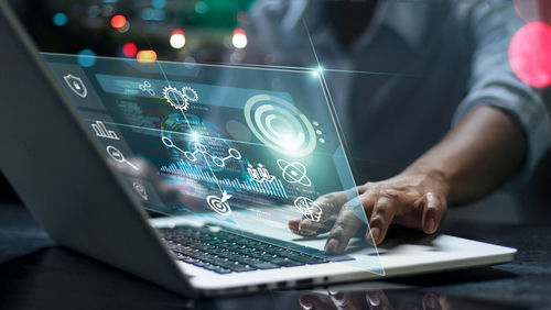 Person using laptop with futuristic data and analytics interface