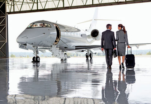 Two businesspeople walking towards a private jet in hangar.