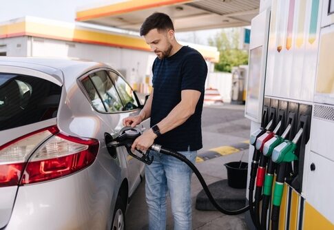 Man fueling a silver car at a gas station
