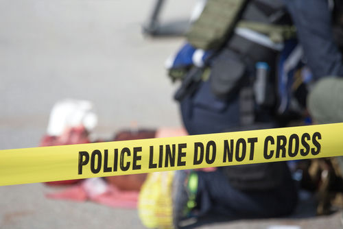 Police tape cordons off an active scene with responders in the background