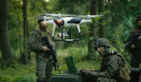 Soldiers in a forest operating a drone.